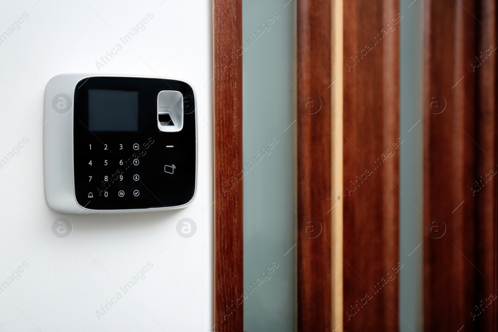 Photo of Modern alarm system with fingerprint scanner on white wall indoors. Space for text