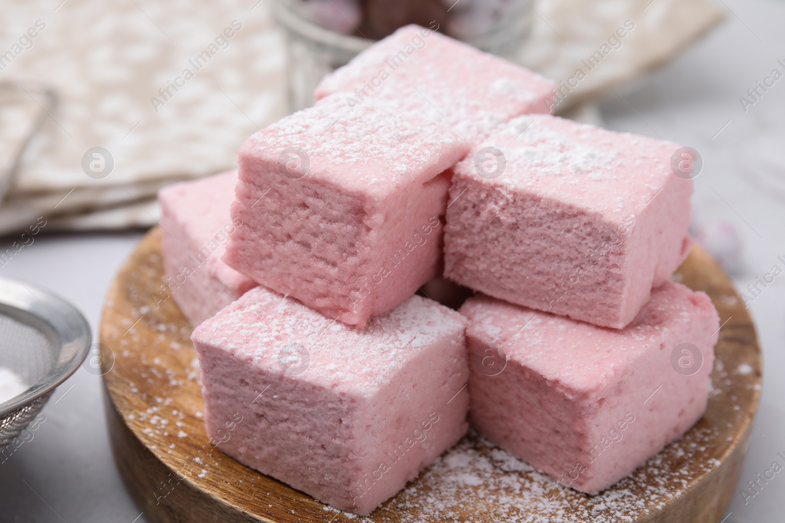 Photo of Tasty marshmallows with powder sugar on white table, closeup