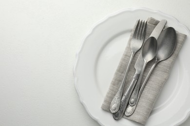 Photo of Stylish setting with cutlery and plate on white textured table, top view. Space for text