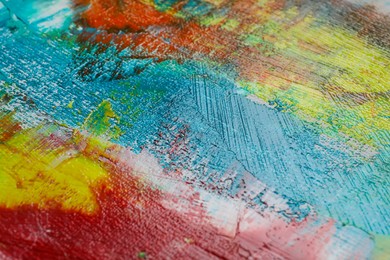 Photo of Strokes of colorful acrylic paints on canvas, closeup