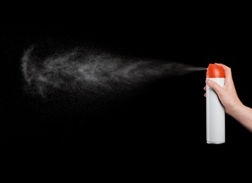 Woman spraying air freshener on black background, closeup