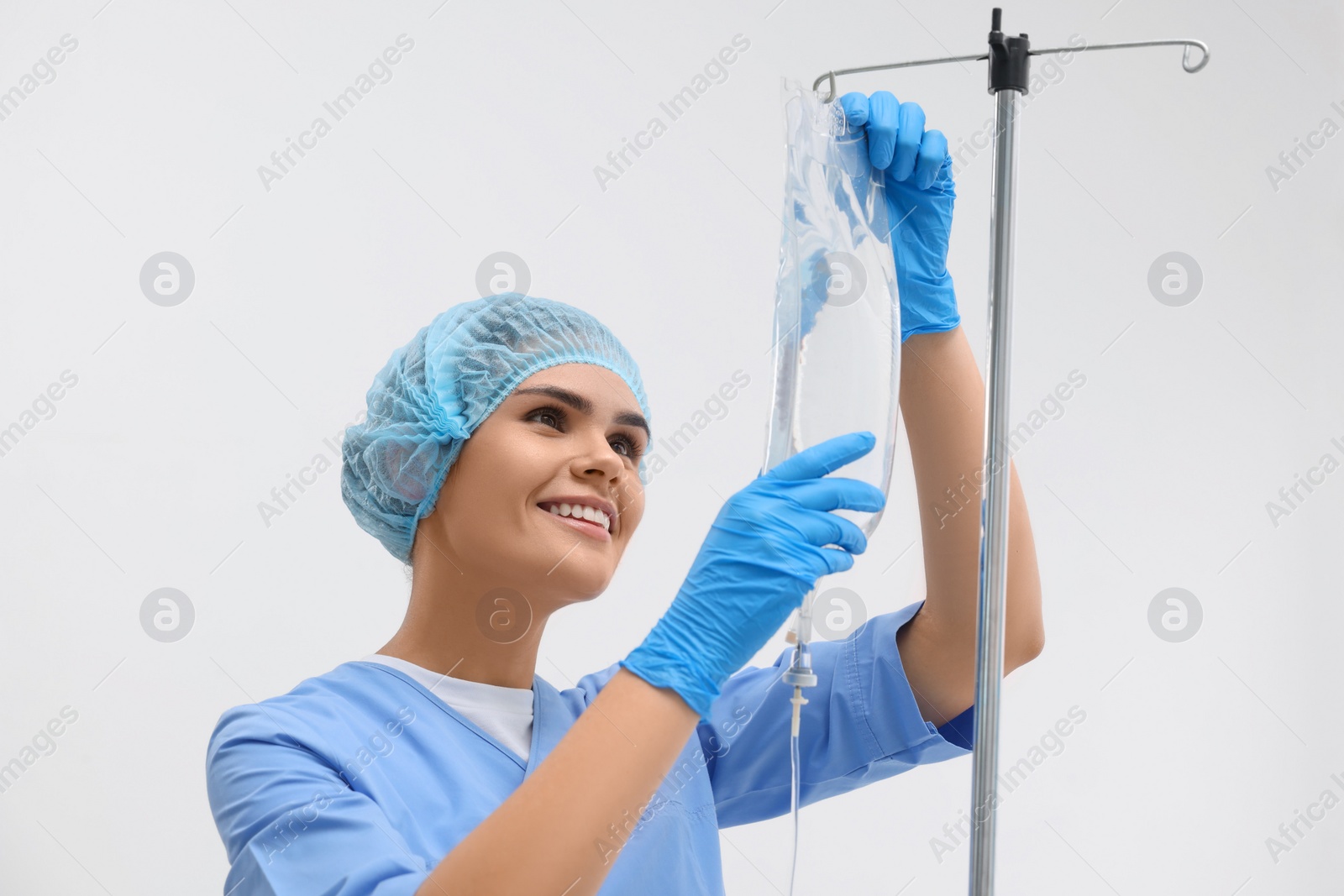 Photo of Nurse setting up IV drip on white background