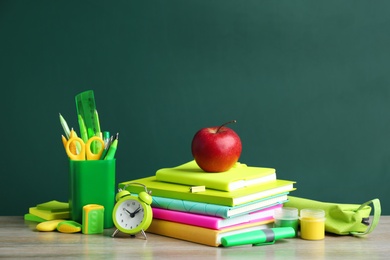 Photo of Different school stationery on wooden table near green chalkboard