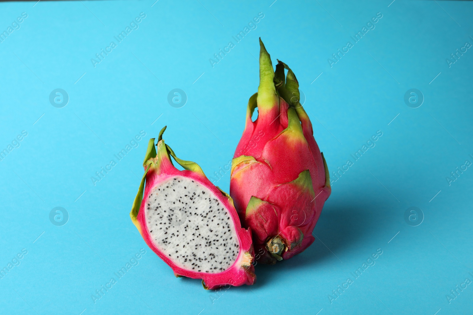 Photo of Delicious cut and whole white pitahaya fruits on light blue background