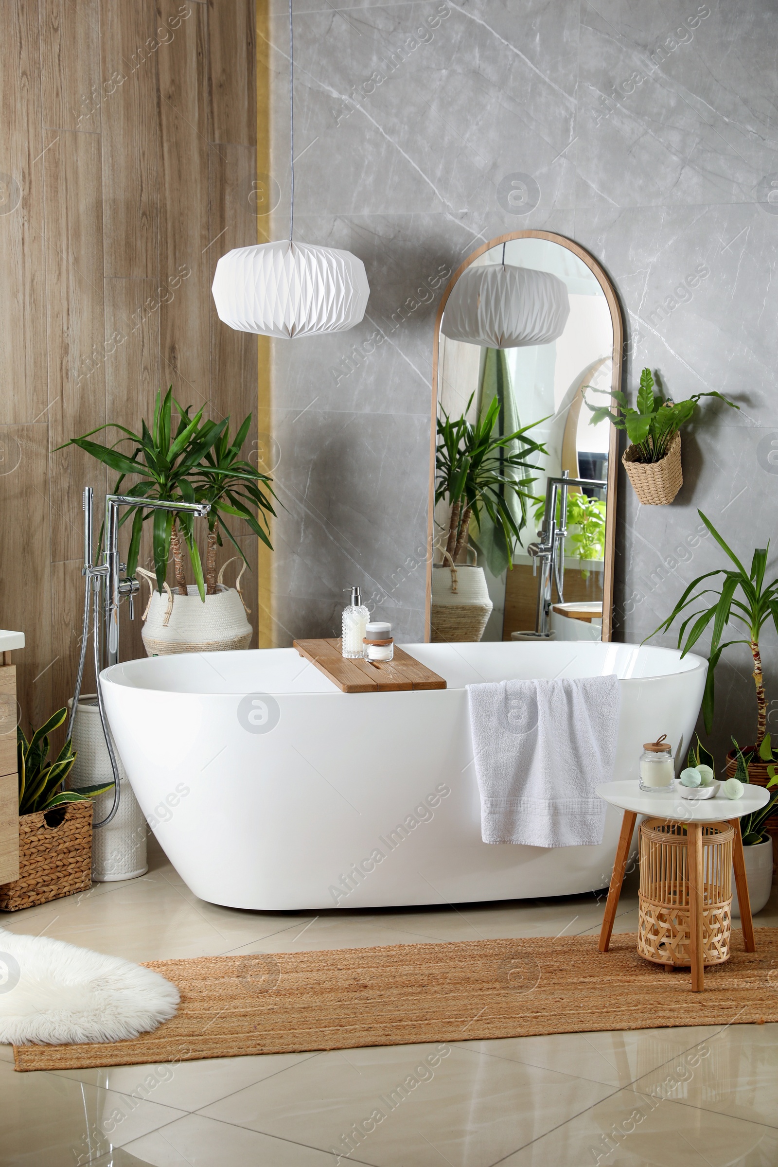 Photo of Modern white tub and beautiful green houseplants in bathroom. Interior design