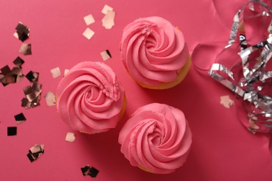 Photo of Delicious cupcakes with bright cream and confetti on pink background, flat lay