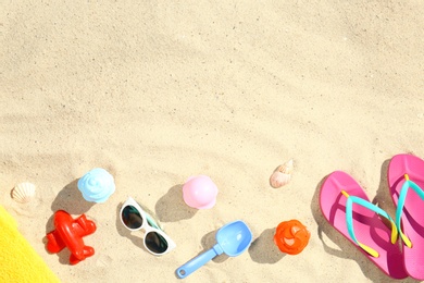 Photo of Flat lay composition with plastic beach toys on sand. Space for text