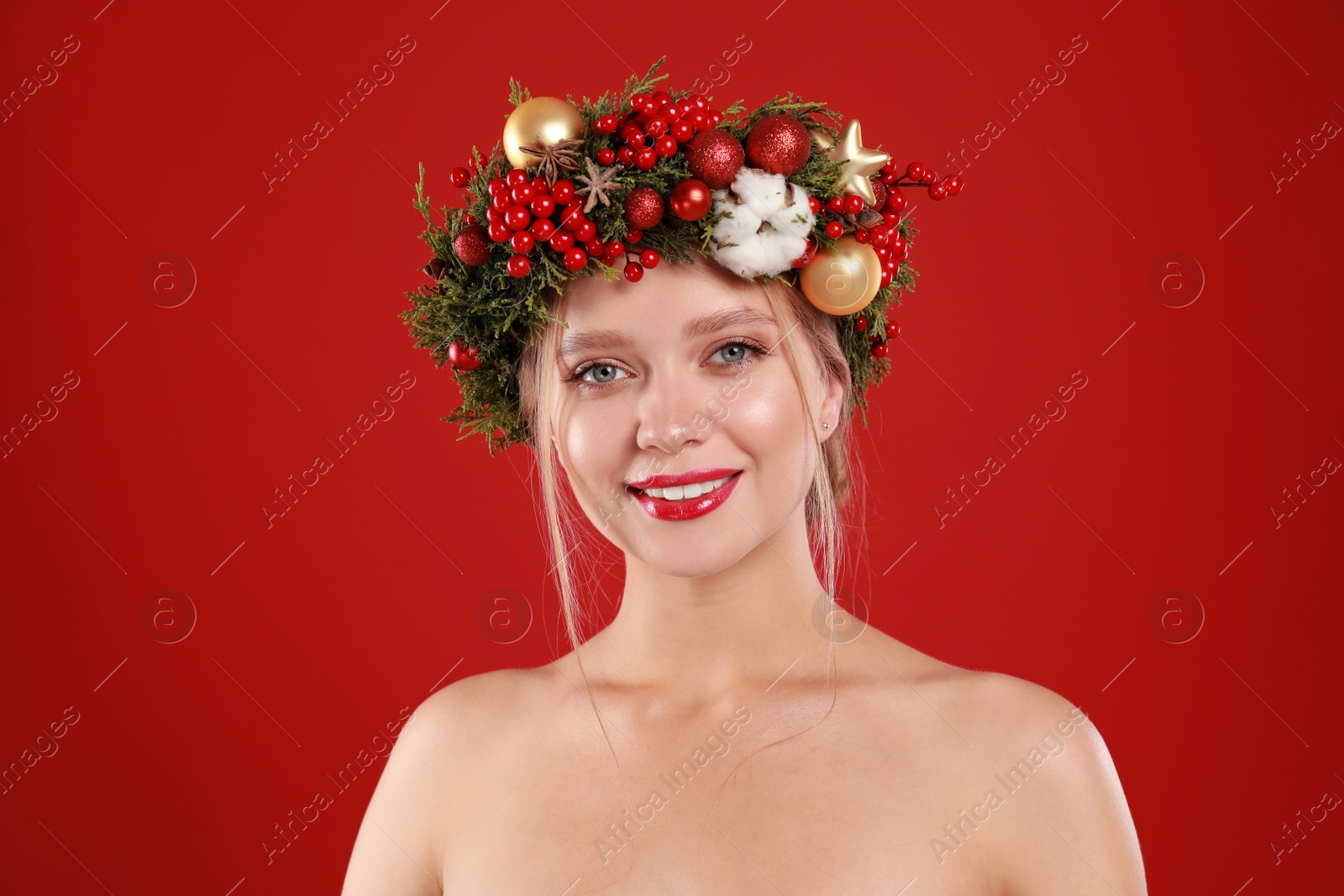 Photo of Beautiful young woman wearing Christmas wreath on red background