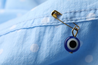 Evil eye safety pin on clothing, closeup