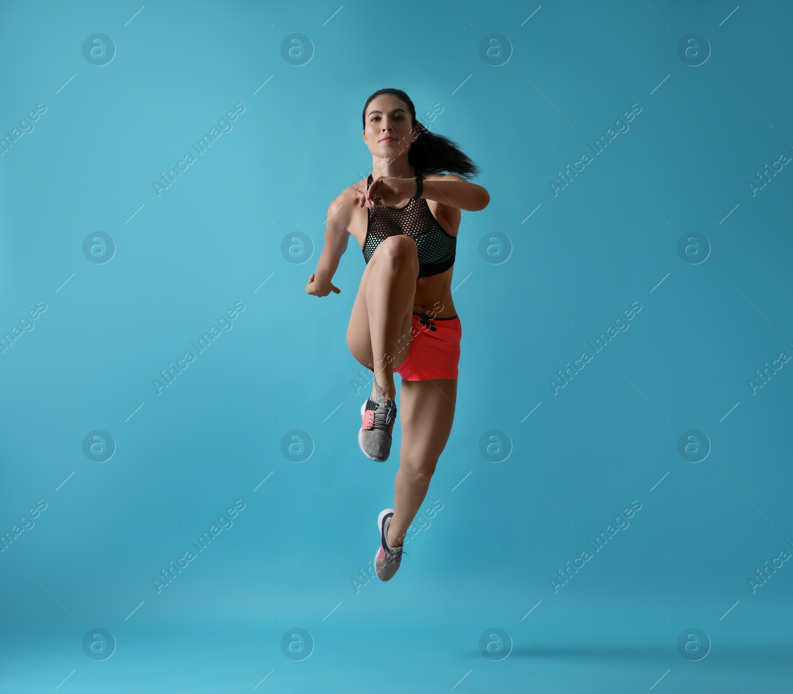 Photo of Athletic young woman running on light blue background