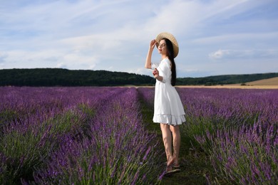 Beautiful young woman walking in lavender field
