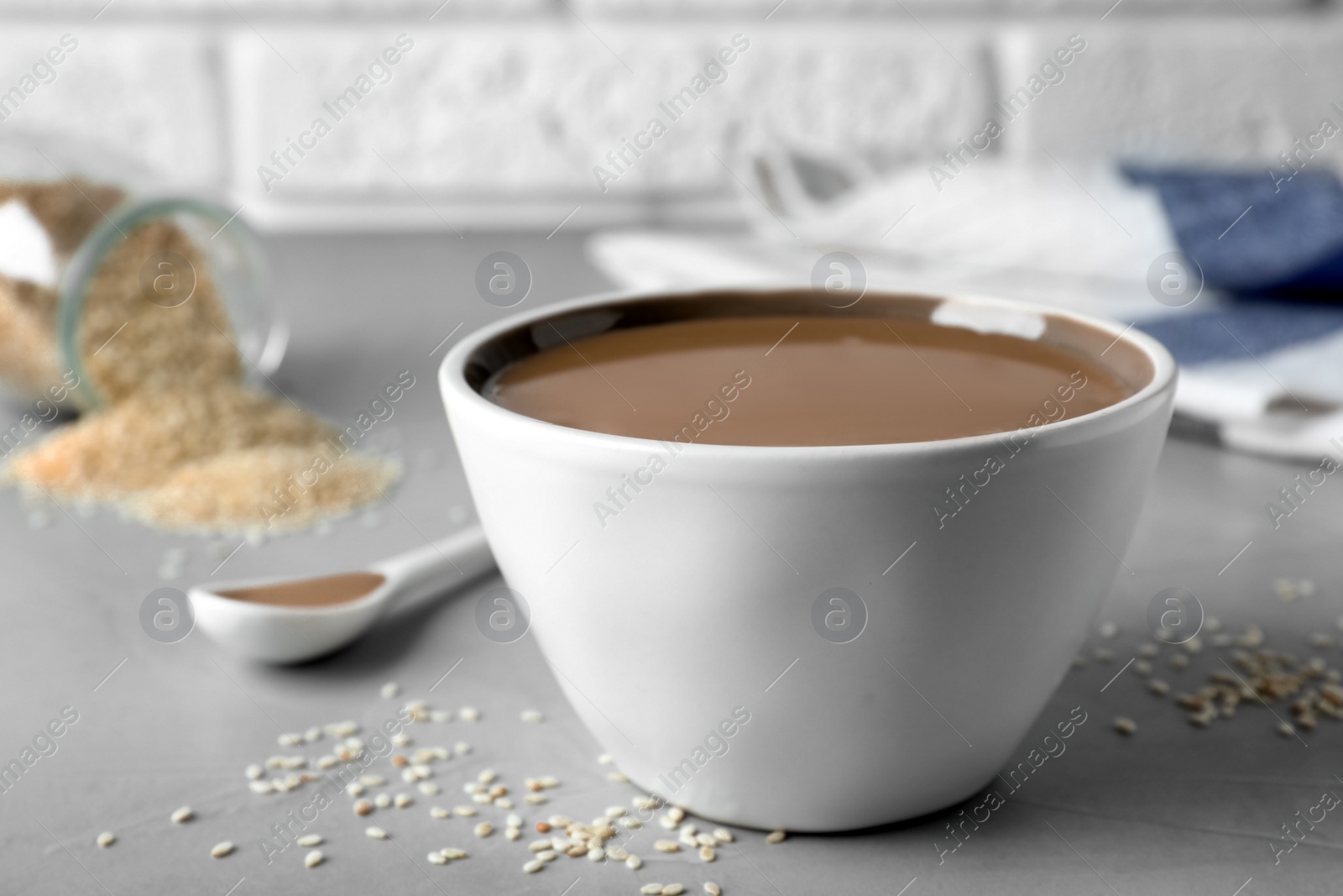 Photo of Tasty sesame paste in bowl on light grey table, closeup