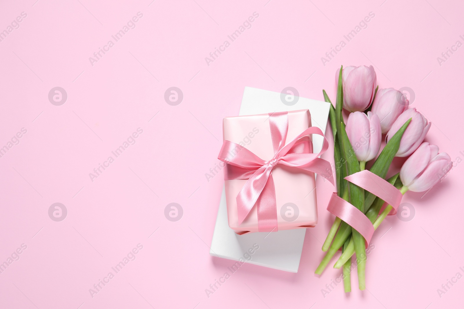 Photo of Beautiful gift box and tulips on pink background, flat lay. Space for text