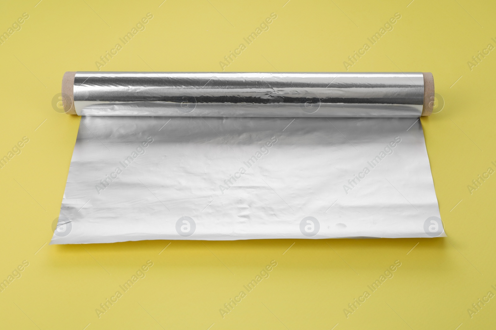 Photo of Roll of aluminum foil on yellow background