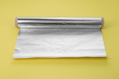 Photo of Roll of aluminum foil on yellow background