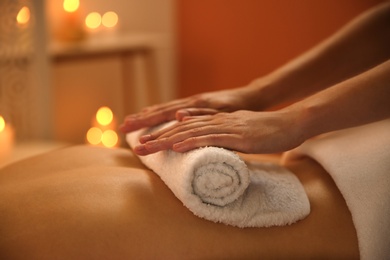 Photo of Young woman receiving hot towel massage in spa salon, closeup