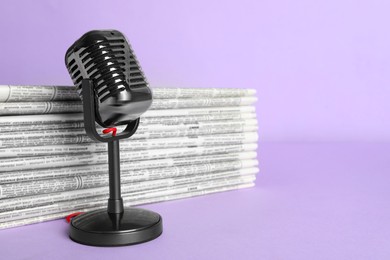 Photo of Newspapers and vintage microphone on light violet background, space for text. Journalist's work