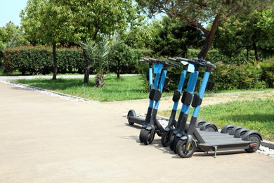 Photo of Many modern electric scooters in park, space for text. Rental service