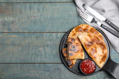 Photo of Delicious fried chebureki with ketchup served on light blue wooden table, flat lay. Space for text