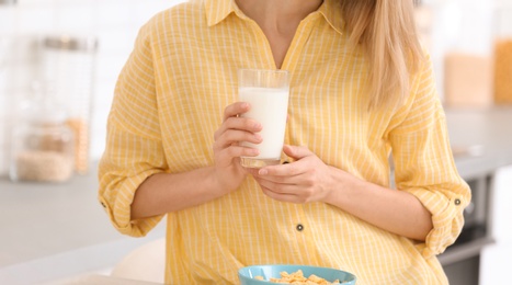 Photo of Beautiful young woman drinking milk in kitchen