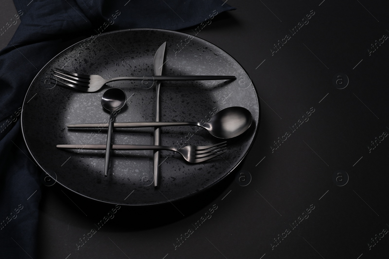 Photo of Stylish table setting. Plate, napkin and cutlery on black background, space for text