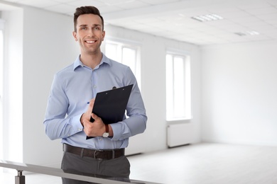 Male real estate agent with clipboard indoors