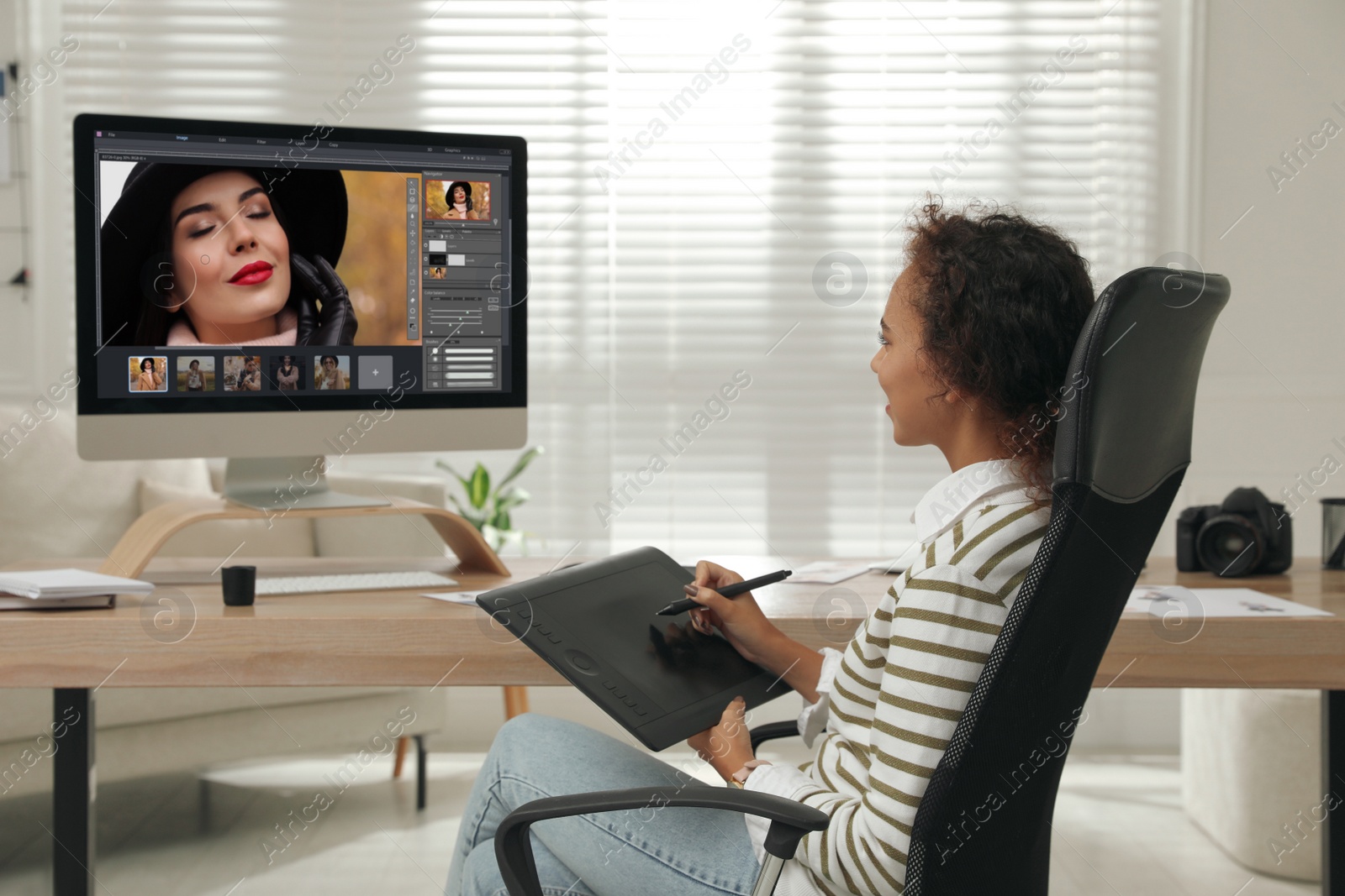 Photo of Professional African American retoucher working with graphic tablet at desk in office