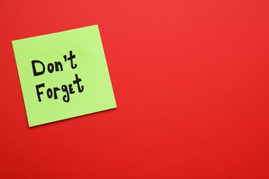Photo of Paper note with phrase Don't Forget on red background, top view. Space for text