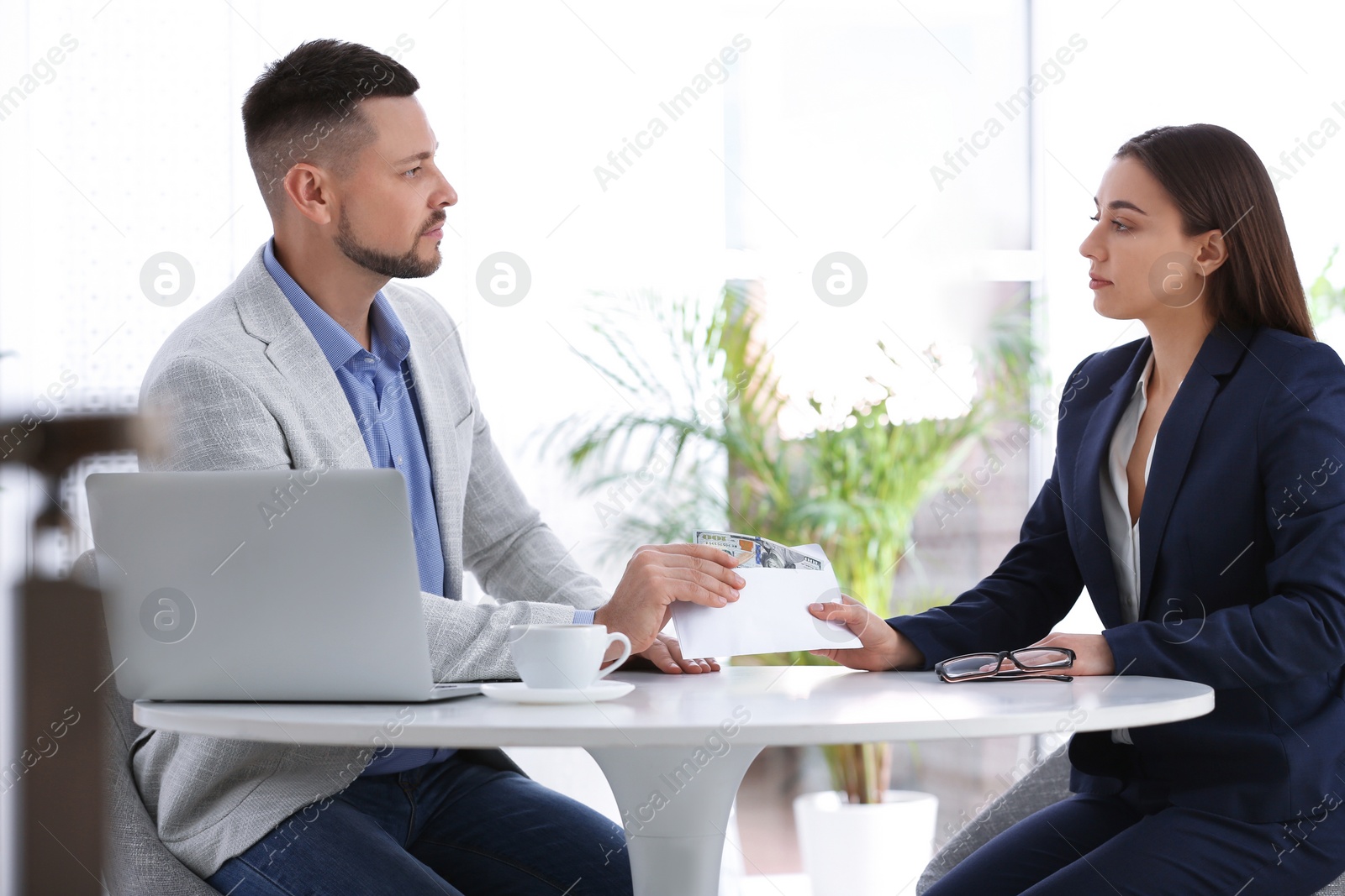 Photo of Woman giving bribe to man at table indoors