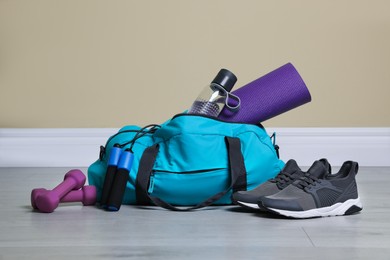 Photo of Bag with different sports equipment on wooden floor indoors