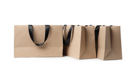 Paper shopping bags with ribbon handles on white background. Mockup for design