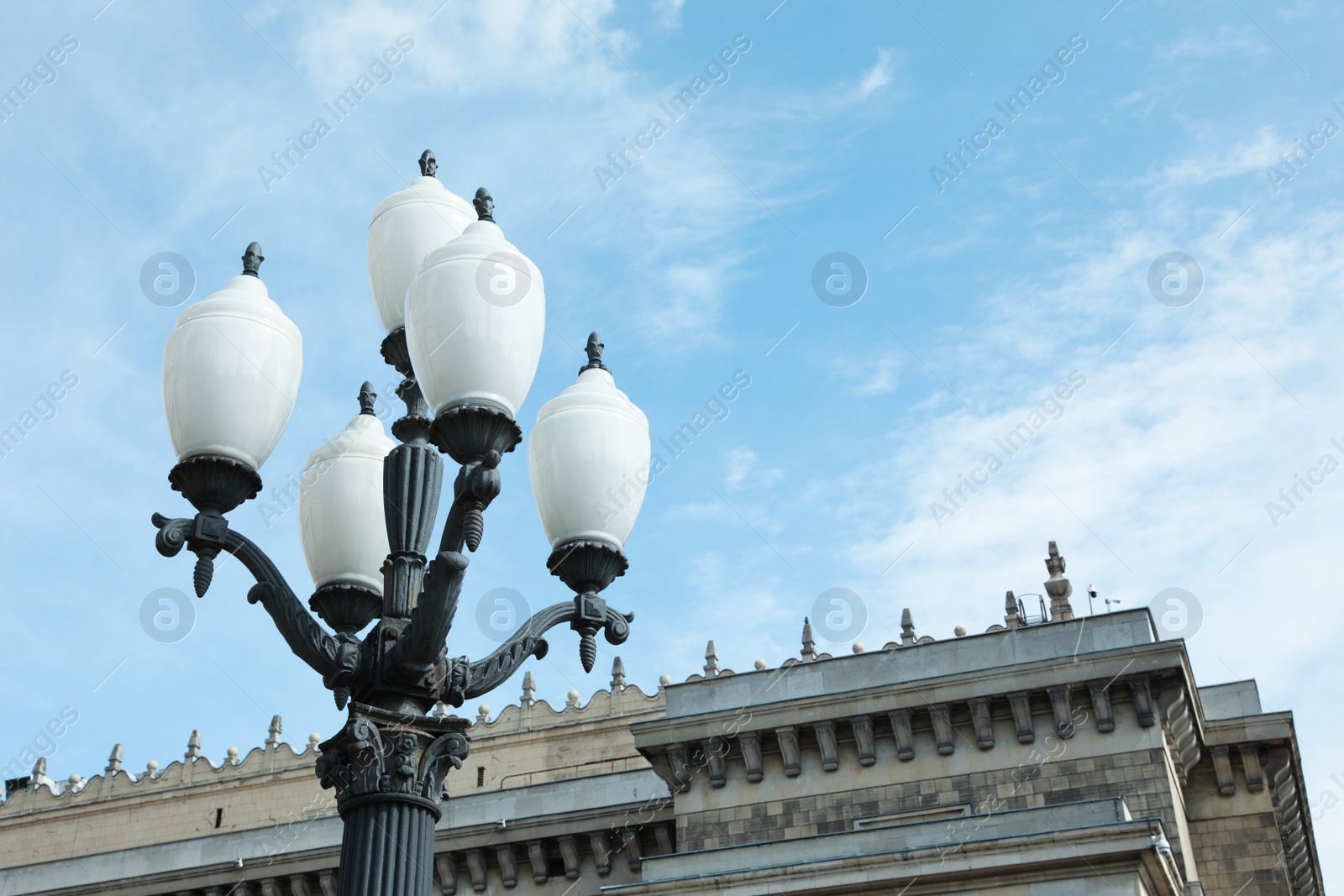 Photo of Old fashioned street light lamp near building against cloudy sky