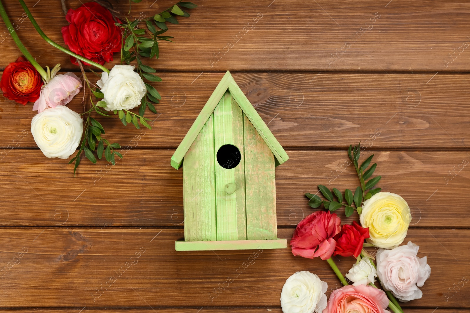 Photo of Stylish bird house and fresh eustomas on wooden background, flat lay