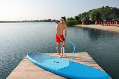 Man pumping up SUP board on pier
