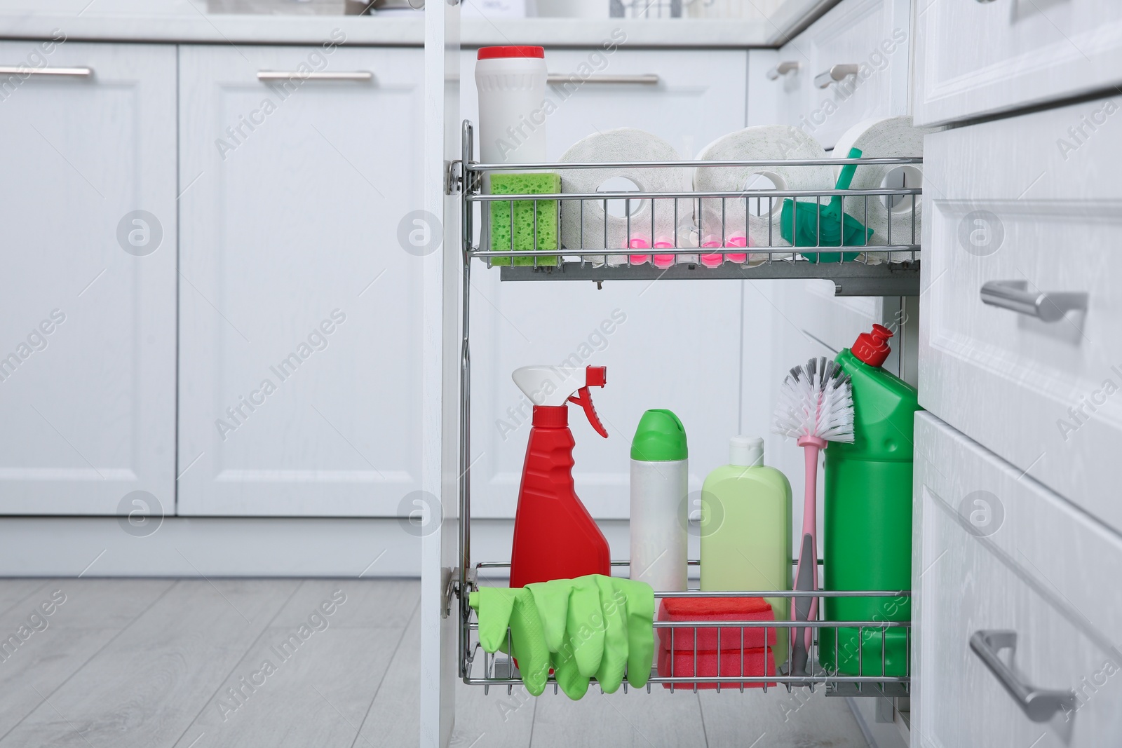 Photo of Open drawer with different cleaning supplies in kitchen. Space for text