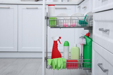 Photo of Open drawer with different cleaning supplies in kitchen. Space for text