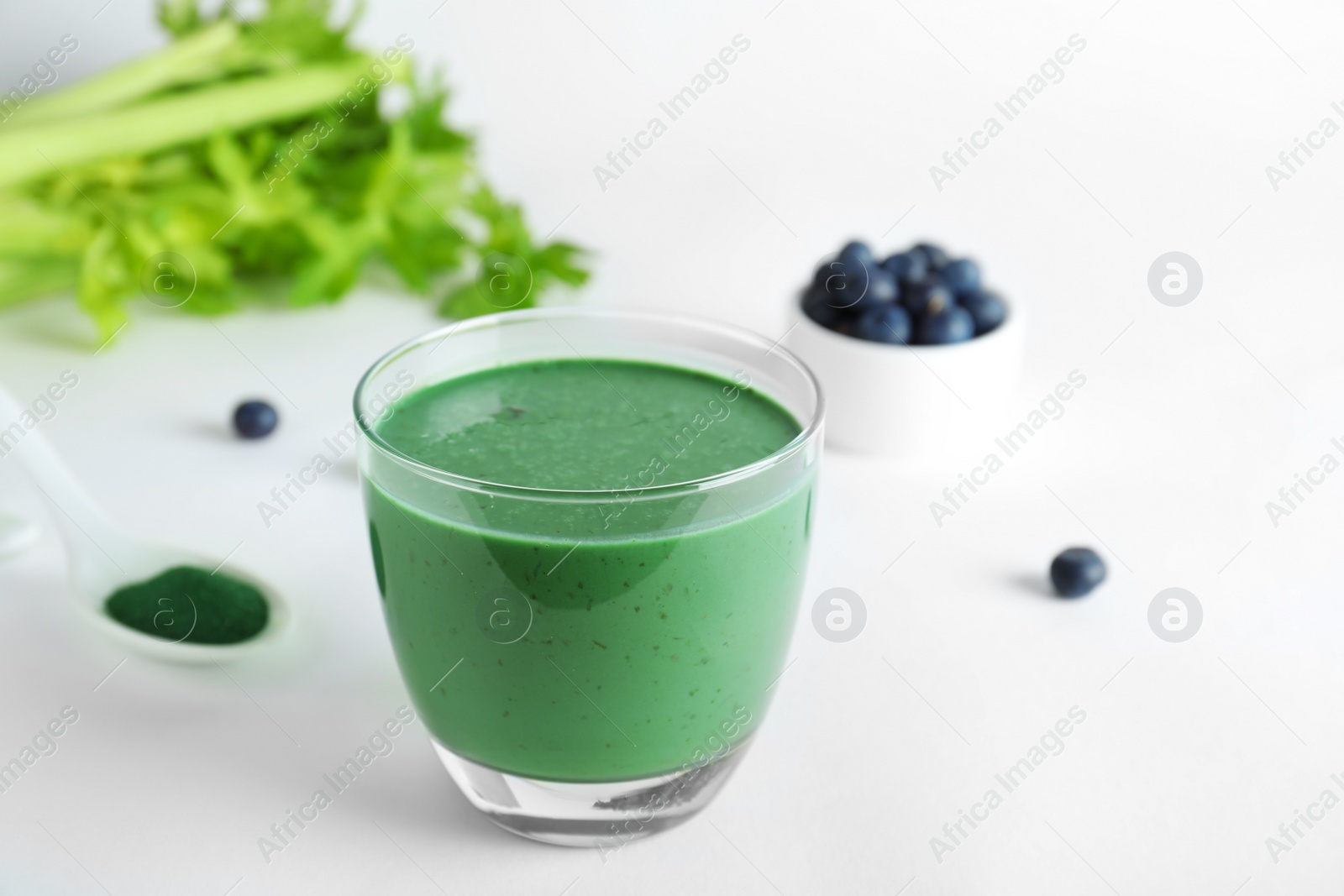 Photo of Composition with glass of spirulina smoothie on white background. Space for text