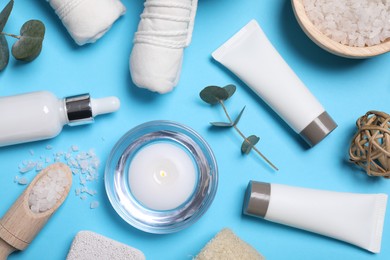 Flat lay composition with spa products and eucalyptus branches on light blue background