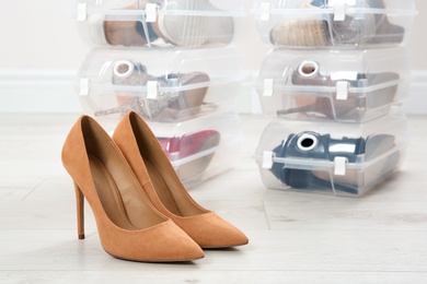 Pair of female shoes and other footwear in plastic boxes on floor. Storage organization