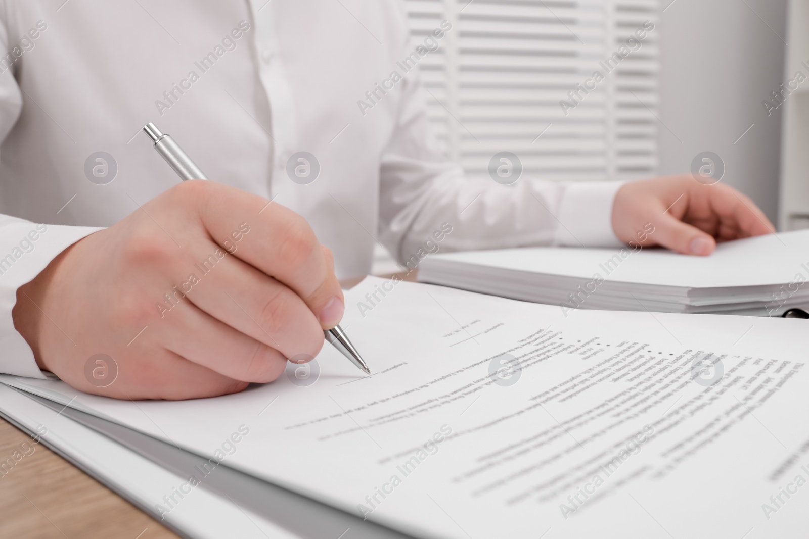 Photo of Man signing document at table, closeup view