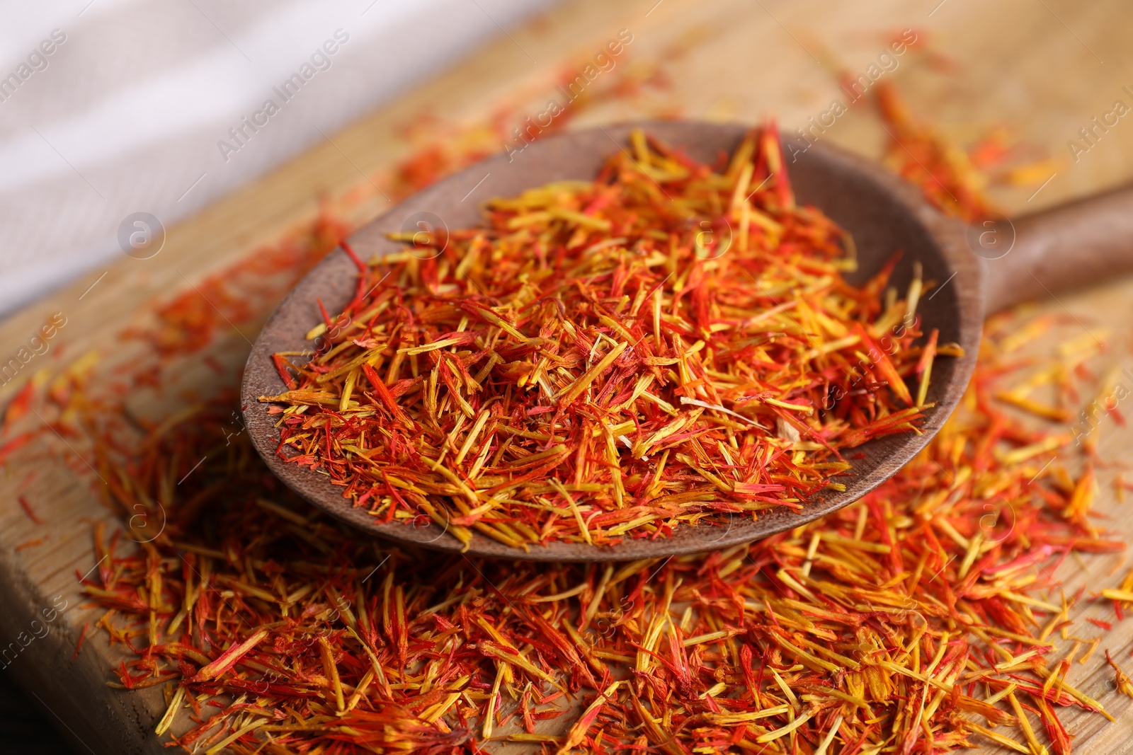 Photo of Aromatic saffron and spoon on wooden table, closeup