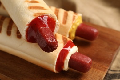 Photo of Delicious french hot dogs on wooden board, closeup