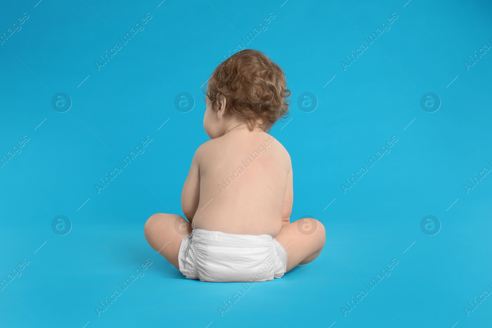 Photo of Cute little baby in diaper on light blue background