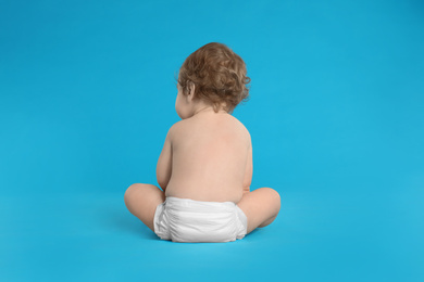 Photo of Cute little baby in diaper on light blue background