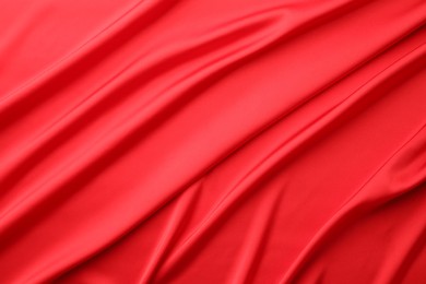 Crumpled red silk fabric as background, top view