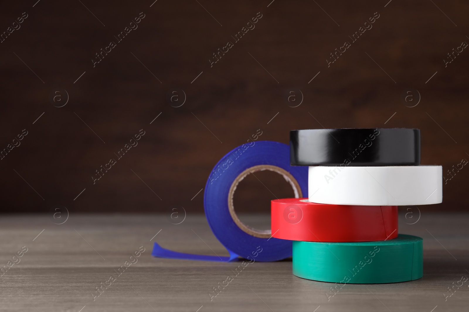 Photo of Colorful insulating tapes on wooden table. Space for text