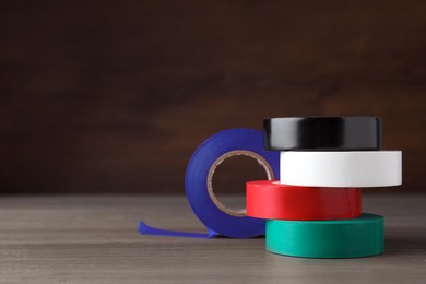 Photo of Colorful insulating tapes on wooden table. Space for text