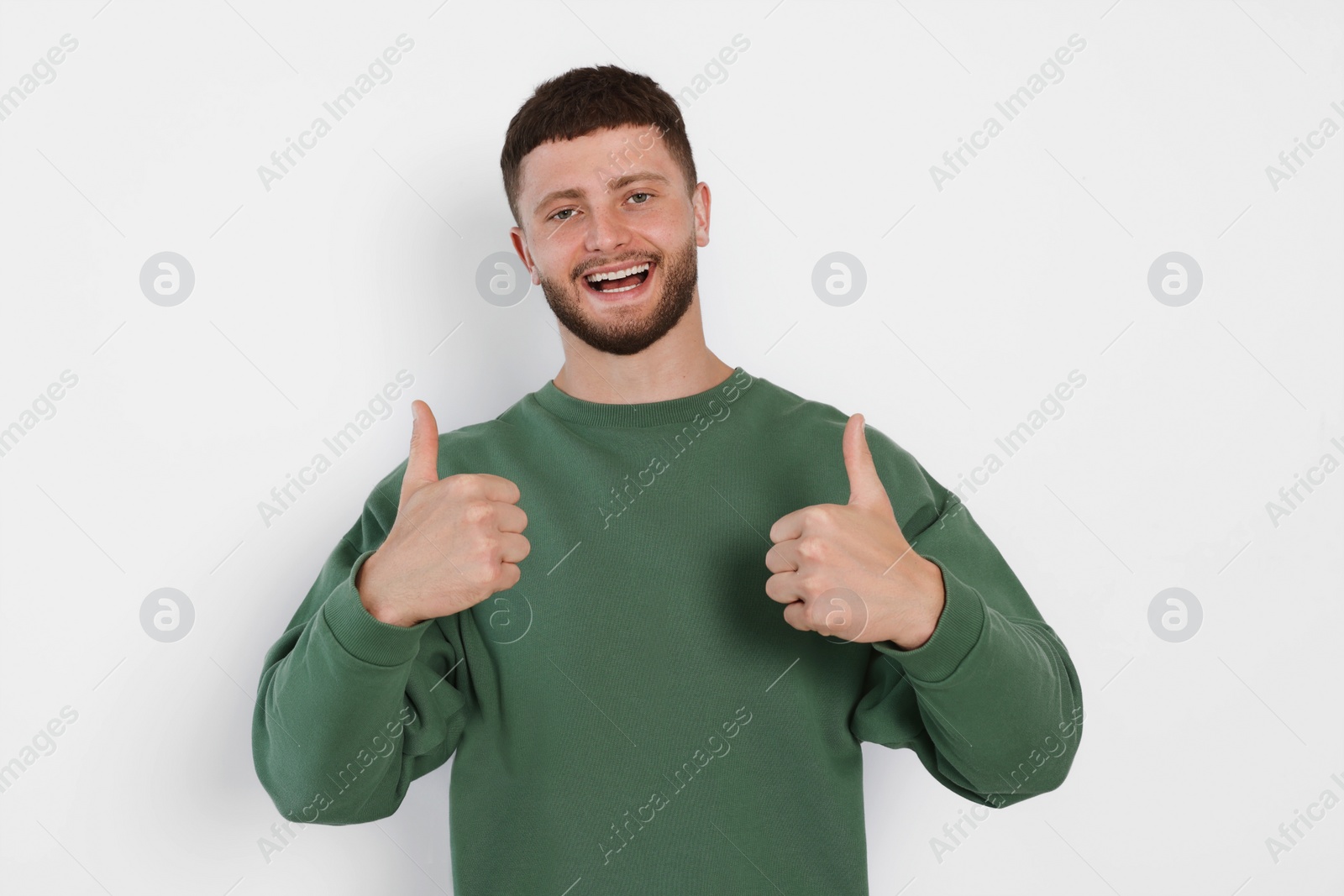 Photo of Young man showing thumbs up on white background