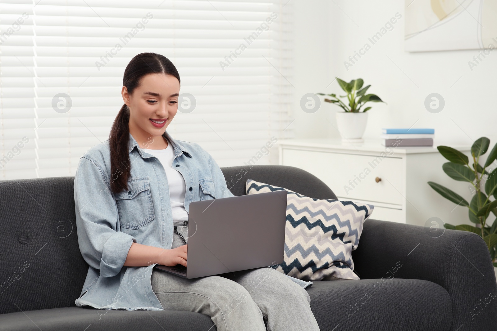 Photo of Woman using laptop on couch at home