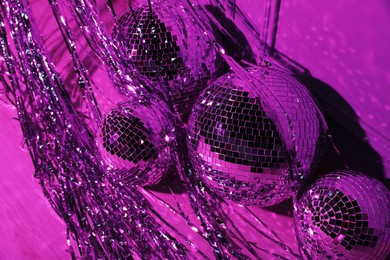 Photo of Shiny disco balls and foil fringe curtain indoors, toned in purple